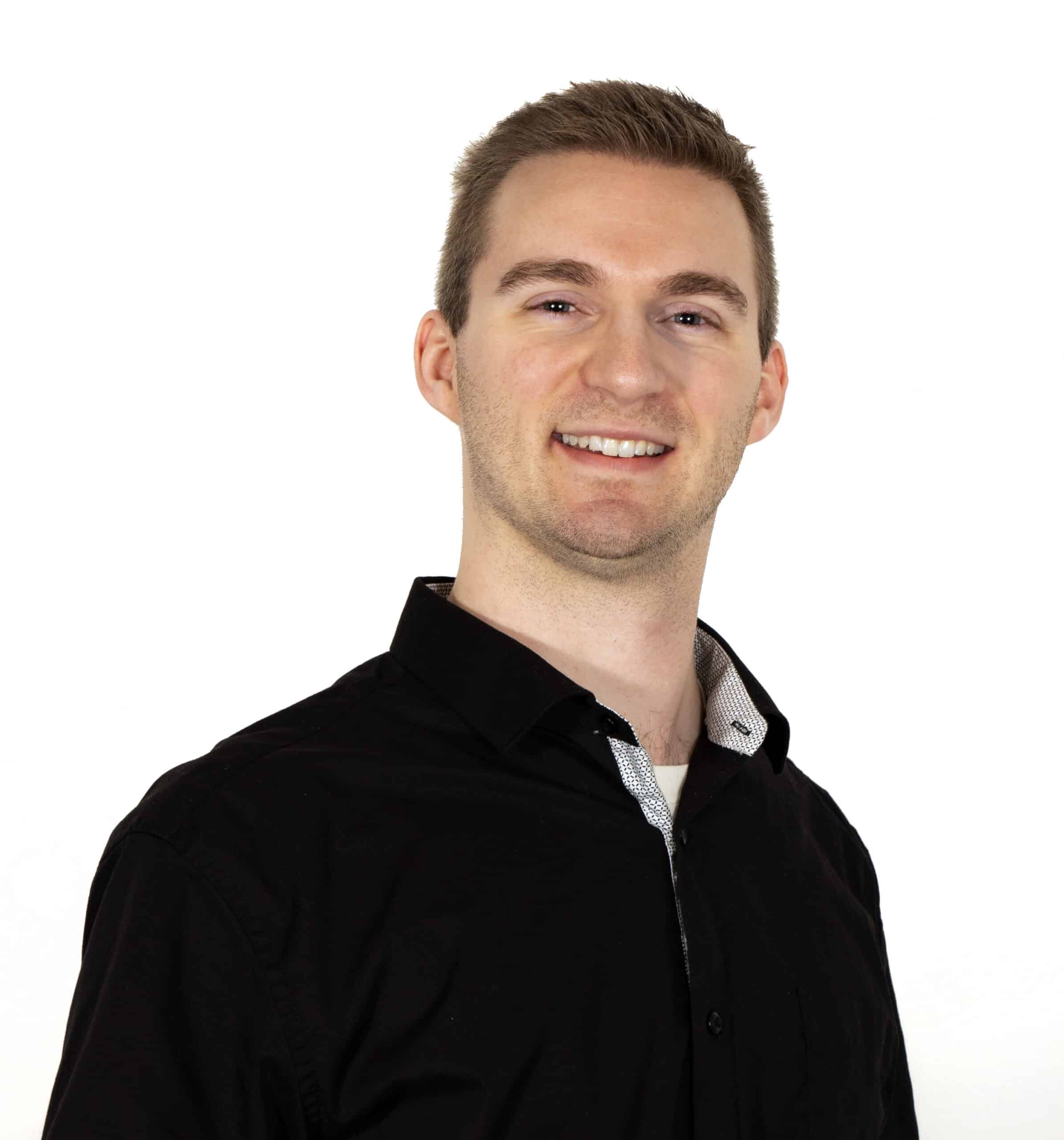 Headshot of a man with short hair, wearing a black polo, smiling in front of white background