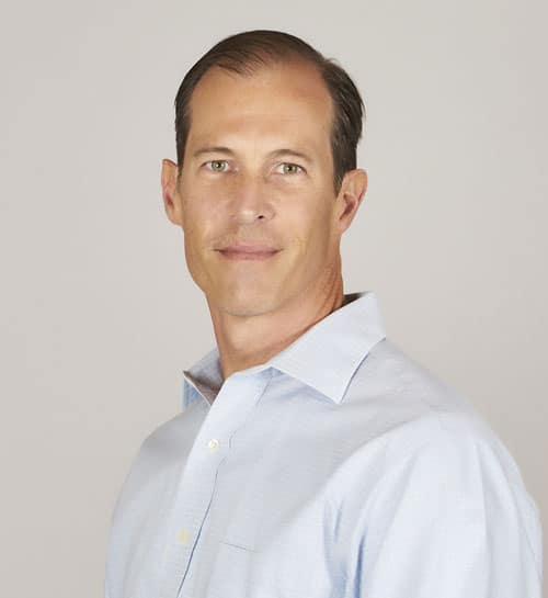 Headshot of a man with short brown hair and light eyes, wearing a collared shirt