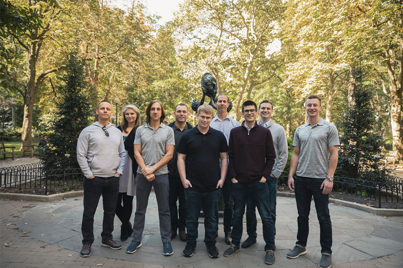 Small group of people standing outside in a park setting, posing for a photo