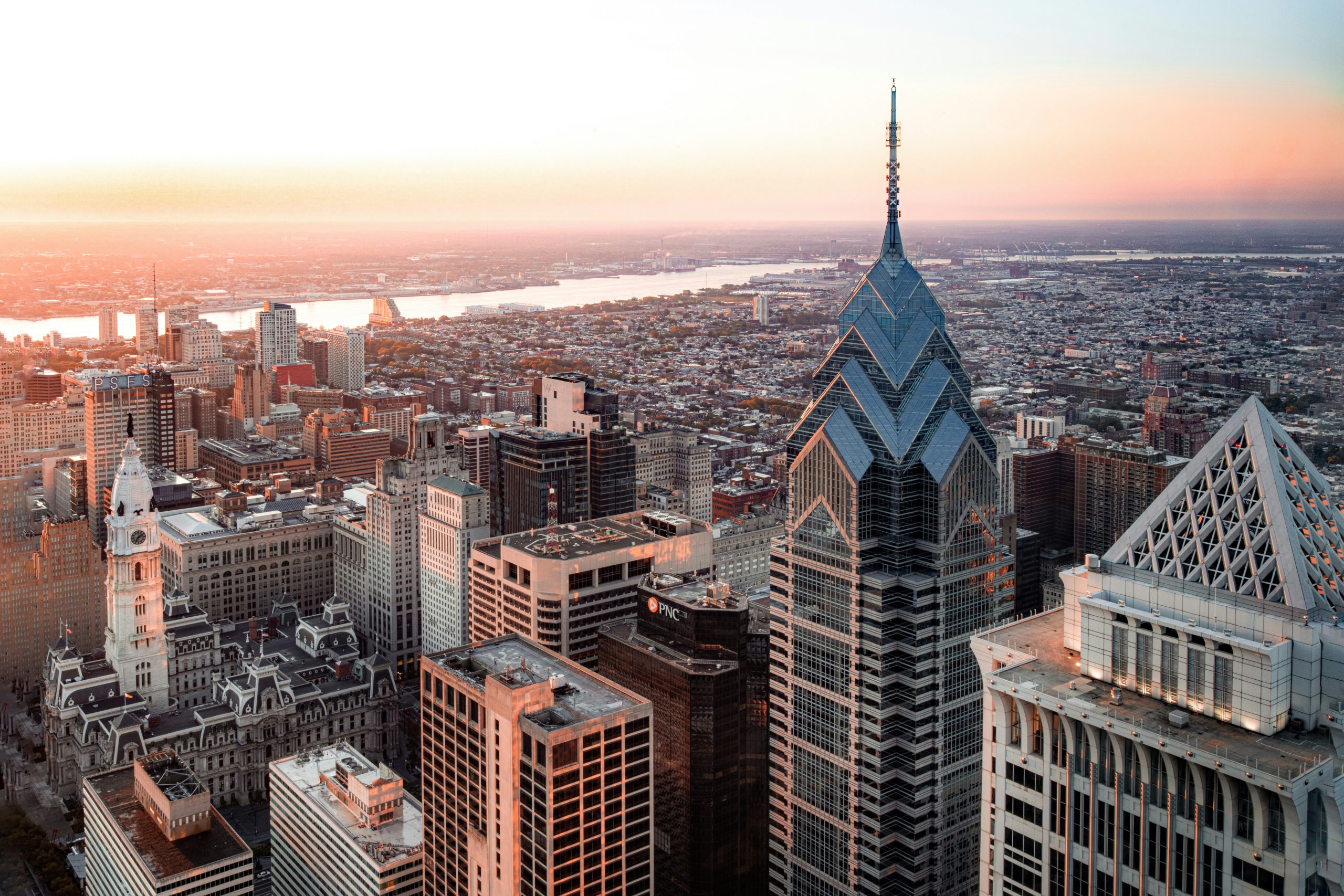 Aerial view of a city skyline at sunset, featuring a pointed high-rise building